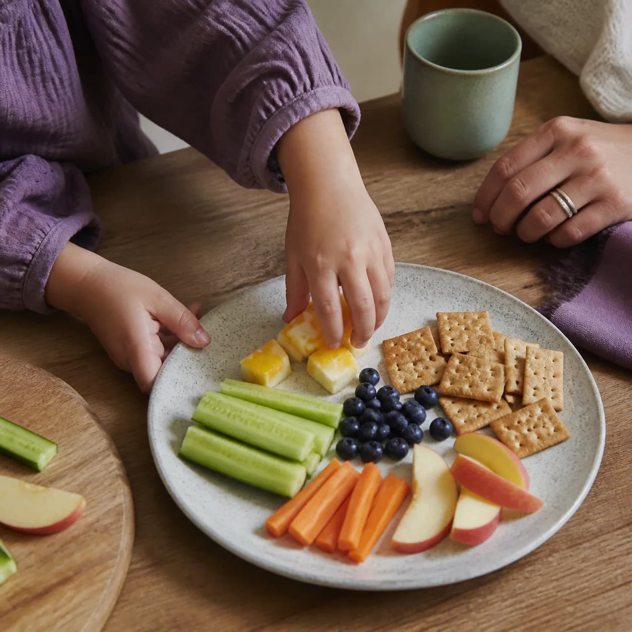 Child and caregiver choosing foods together at a kitchen table
