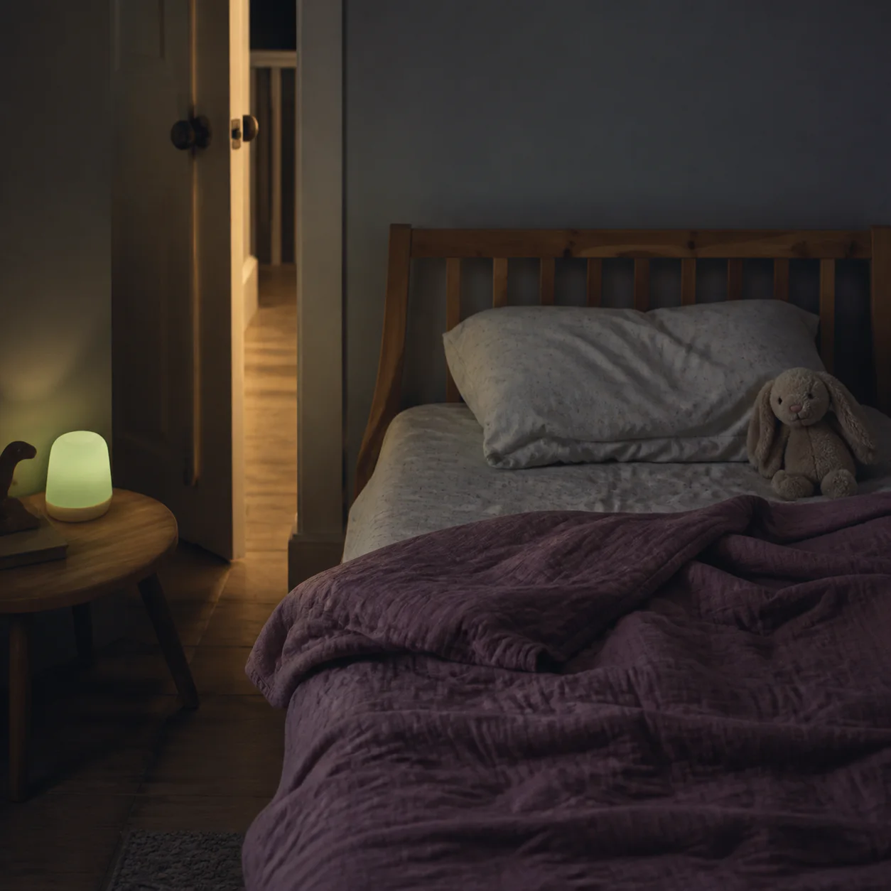 Rumpled child's bed beneath a soft night-light